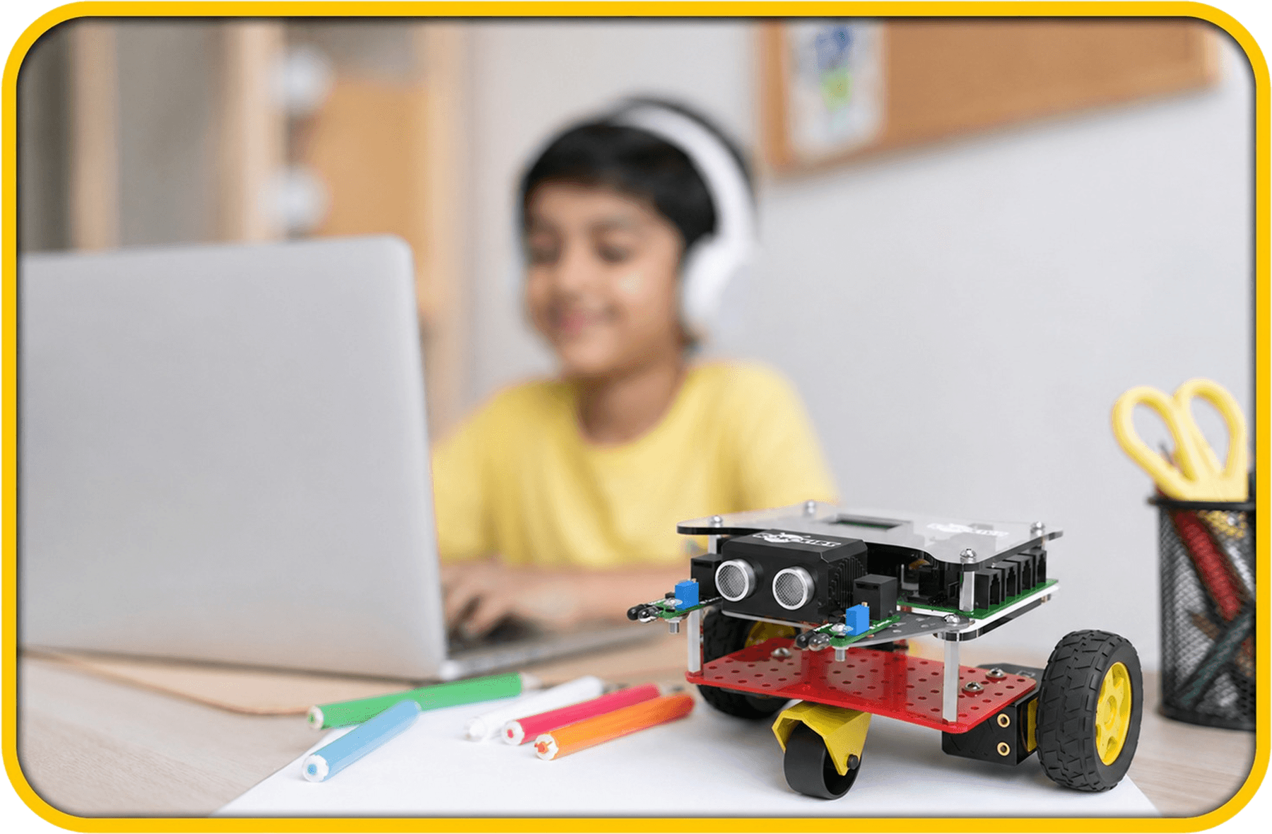 A child at a laptop with a Robokidz robot on the desk
